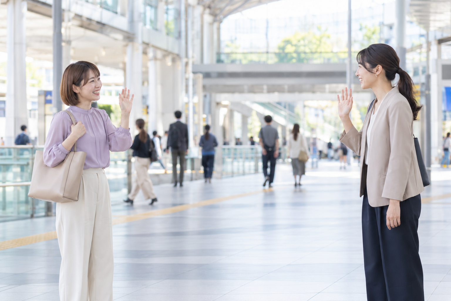 明るい駅構内で待ち合わせる成人女性二人のイメージ
